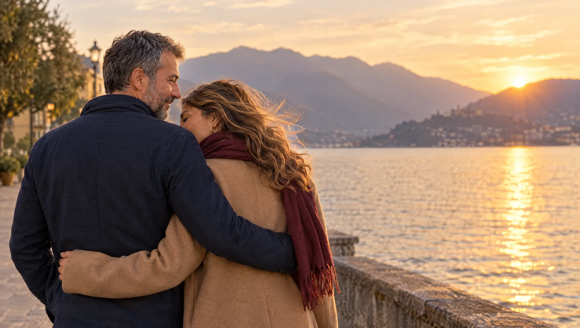 Lei e lui abbracciati sul lungolago al tramonto